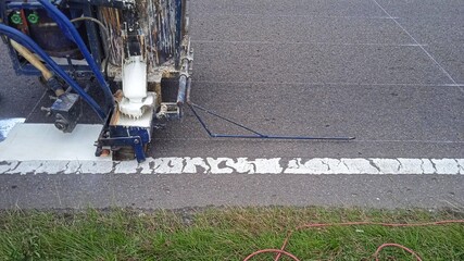 Road workers use hot-melt scribing machines to painting dividing line on asphalt road surface in the city.