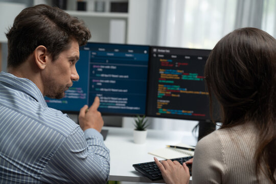 Team skilled developers program coding discussing creative website planning software project on two screen monitor's full stack data analyzing design at office with back side view concept. Postulate.