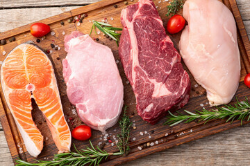 Mix of raw meat and fish . Salmon , beef , pork , chicken staek . Top view