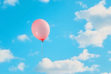  A pink balloon floats against a bright blue sky with fluffy clouds. © Sebelas Studio
