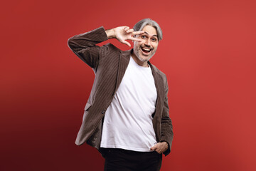 man in striped blazer smiling, making the peace symbol with his right hand