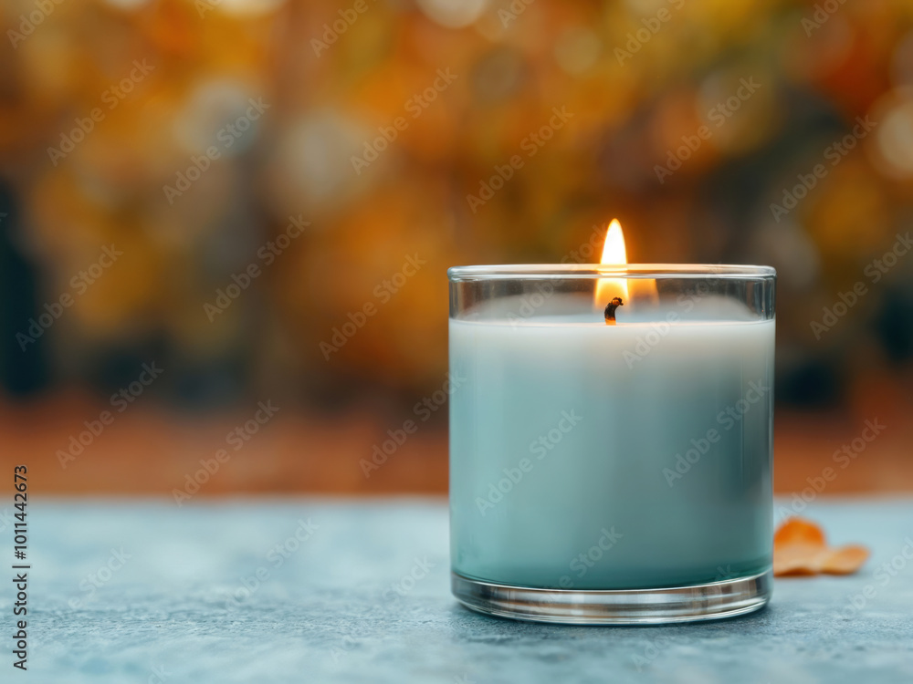 Poster burning teal candle on empty table with autumn background