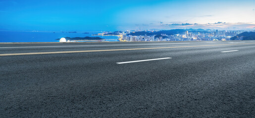 Fototapeta premium Scenic Highway Overlooking a Vibrant City Skyline and Ocean View at Dusk