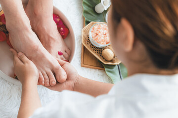 Woman indulges in blissful foot massage at luxurious spa salon while masseur give reflexology therapy in gentle day light ambiance resort or hotel foot spa. Quiescent