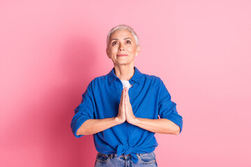 Photo of cheerful dreamy lady dressed blue shirt praying looking up empty space isolated pink color...