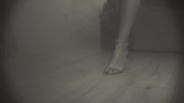 Old film 1920s style black and white color Retro lady feet legs close-up shoot shoes sandals classic high heels walking on wooden parquet roarind twenties party. Happy sexy woman. Girl body part 4k