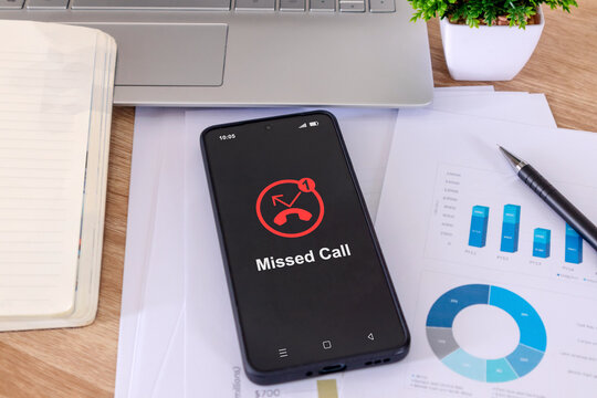 A mobile phone on a desk with a missed call notification on the phone screen