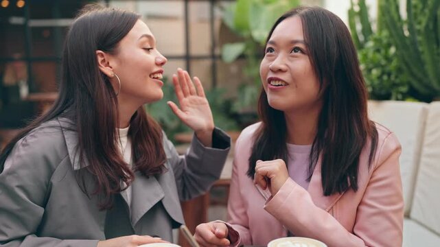 Two friends catching up and gossiping at a cozy cafe, sharing secrets over coffee cups on a sunny day.