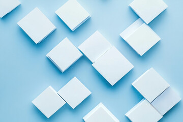 A creative arrangement of blank square papers on a soothing blue backdrop during a quiet afternoon