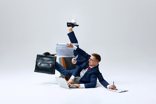 Businessman juggling multiple tasks, papers flying as he multitasks on floor. Overloaded but determined to stay on top of his workload. Concept of business, multitasking, stress, busy lifestyle