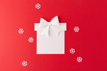 a flat lay composition of a white paper cutout in the shape of a gift with a bow on top, centered...