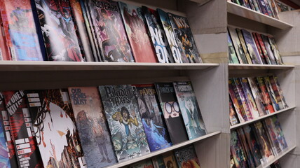 Obraz premium CARDIFF, MID GLAMORGAN, WALES UK - OCTOBER 3, 2024: COMIC BOOKS ON SHELVES DISPLAY PAPERBACKS 