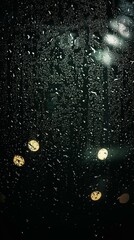 Obraz premium CloseUp of Water Droplets on Glass with Blurred City Lights in a Moody Urban Rainfall Scene