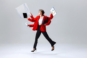 Businesswoman leaping through air, holding tablet, clipboard, and coffee, representing modern...