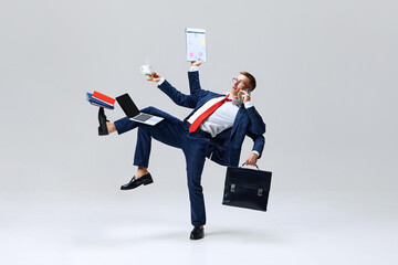 Businessman multitasking, balancing with coffee cup, laptop, and phone in dynamic stance,...