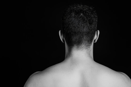 Black and white back view of a shirtless man isolated on dark background