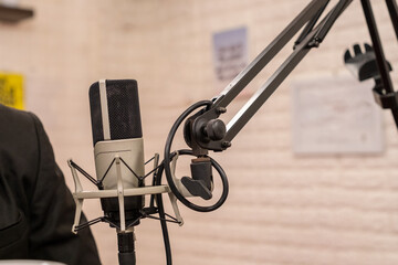 Close-up of a professional studio microphone on a boom arm, perfect for podcasting, recording, or broadcasting. Captures the technical precision and quality of audio equipment in a modern setup.