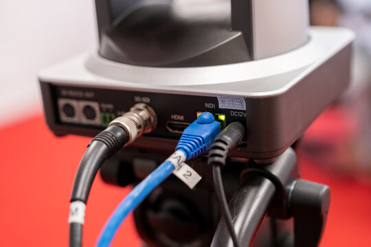 Close-up of camera connections showing HDMI, NDI, and power cables on a video production setup. Professional broadcasting and live streaming equipment with focus on technical details.