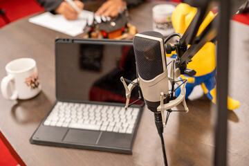 Creative workspace setup featuring a microphone, laptop, and playful character on a vibrant table during a brainstorming session