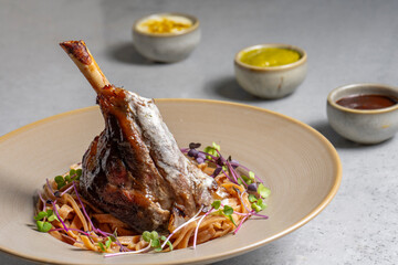 Lamb chop with noodles, sauce and mustard on a gray background