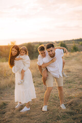 Happy family with children in the park at sunset.