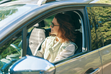 Young happy woman sitting in her car