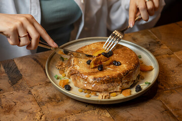 woman eating cake with dried apricots, raisins and walnuts on grey background