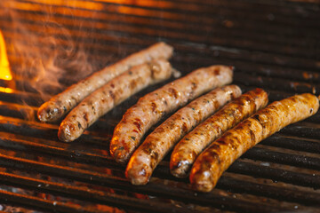 Grilling sausages on the grill with flames and smoke.