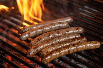 Grilling sausages on the grill with flames and smoke.