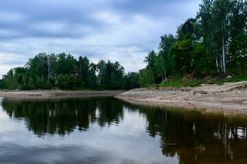 The sun is setting on the banks of the river