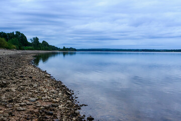 A lake surrounded by tall grass and trees under a cloudy sky.