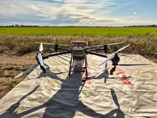 Large agricultural drone in flight, fertilizing a sown field.