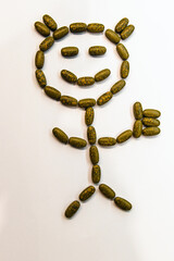 A primitive happy girl made from pills tablets shows a like up with a white background.