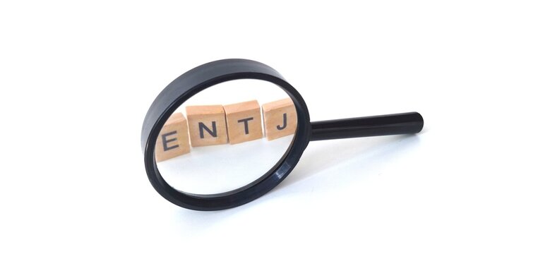 Wooden blocks with ENTJ letters, through a magnifying glass. ENTJ is one of the 16 personality types identified by the Myers-Briggs Type Indicator or MBTI. Extraversion, Intuition, Thinking, Judgement