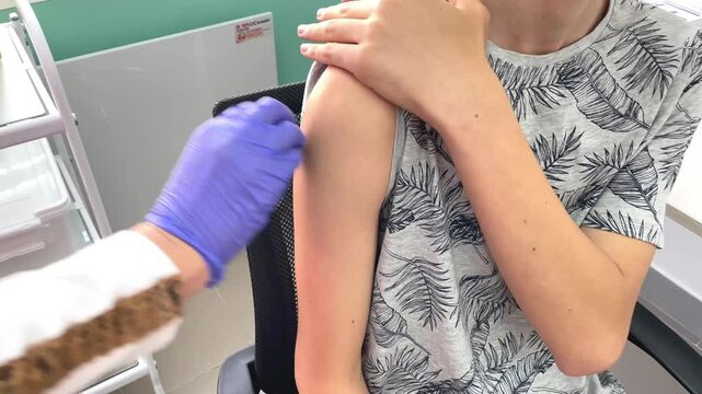 vaccination, professional nurse or doctor giving vaccination to teenager at hospital, getting flu, covid 19 or monkeypox vaccine during mass vaccination and immunization campaign