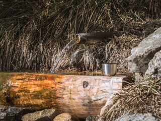 Mountain spring water flowing into a metal cup