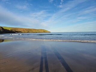 Summer Serenity: Waves Lapping On The Sandy Beach Under A Clear Blue Sky