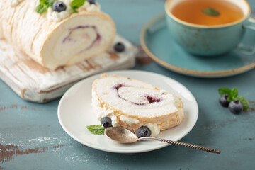 Homemade Meringue Cake Sweets Roll with Blueberry jam and berries  on ceramic plate.
