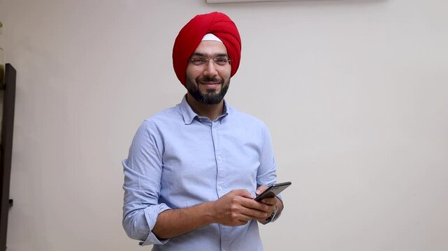 Sikh turban man using phone and smiling towards the camera
