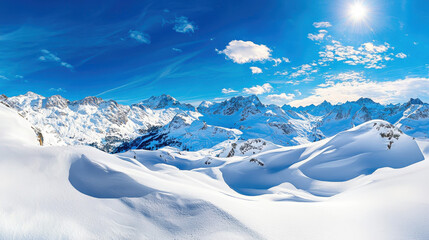 Panoramic view of snow-covered mountain landscape under a bright blue sky with scattered clouds and shining sun
