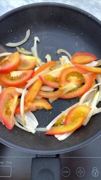 Food preparation of tomatoes and onions for multiple recipes.
