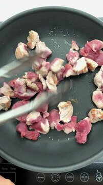 the act of sauteing or tossing delicious pork tenderloin on a cooking hot pan.