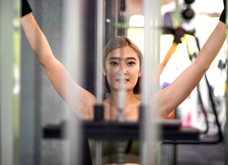 fitness asian woman pulling workout station. beautiful athletic girl pulling heavy system bar using strength. attractive female exerciser workout weight training pulling bar to support body strength