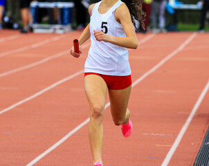 Obraz premium Female runner running in a relay race close up