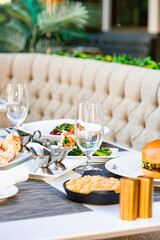 A visually appealing table setting with a variety of dishes, including seafood, salad, and a burger, perfect for a luxurious outdoor dining experience.
