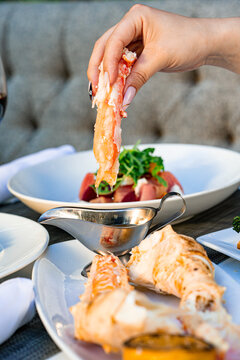 A visually stunning shot of a women dipping crab in butter, including seafood, meat, and side dishes, perfect for a luxurious dining experience.