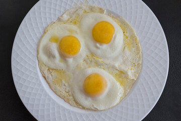 View from above of three fried eggs on a plate