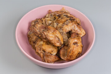 Baked chicken meat in pink bowl on a gray background