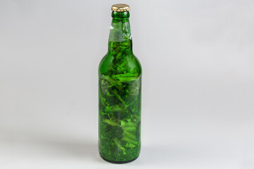 Green bottle filled with cigarette butts mixed with tobacco ash