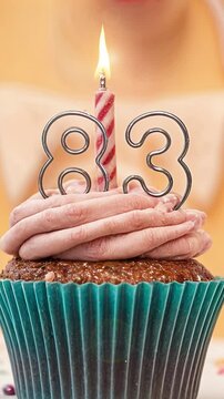 Birthday cupcake with burning lit candle with number 83. Number eighty-three for eighty-three years or eighty-third anniversary.